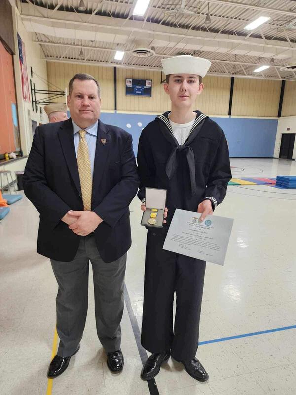 Jameson Lee in dress blues holding a medal and award certificate