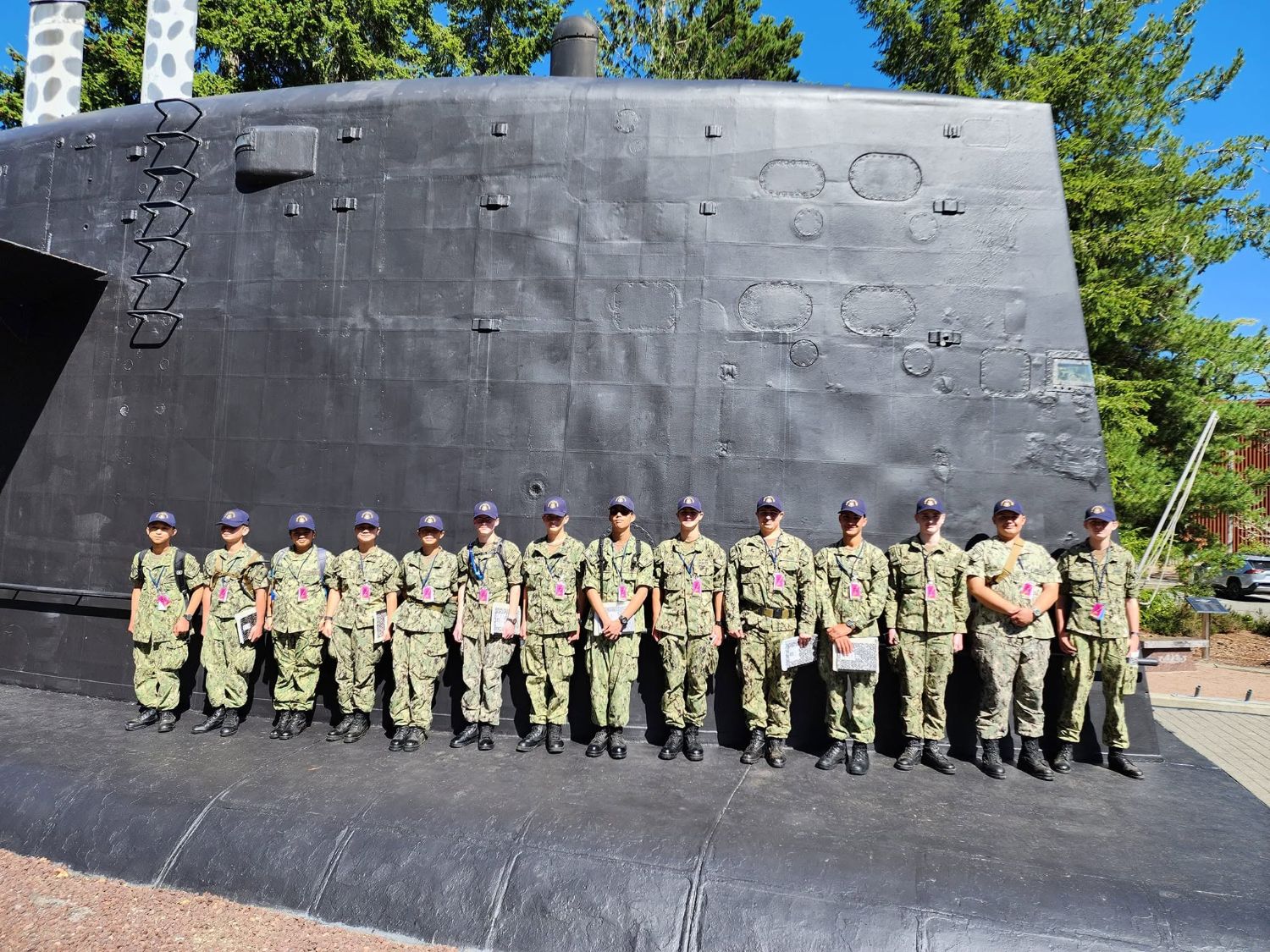 Sea Cadets in Navy Working Uniforms lined up in front of a submarine sail during submarine training