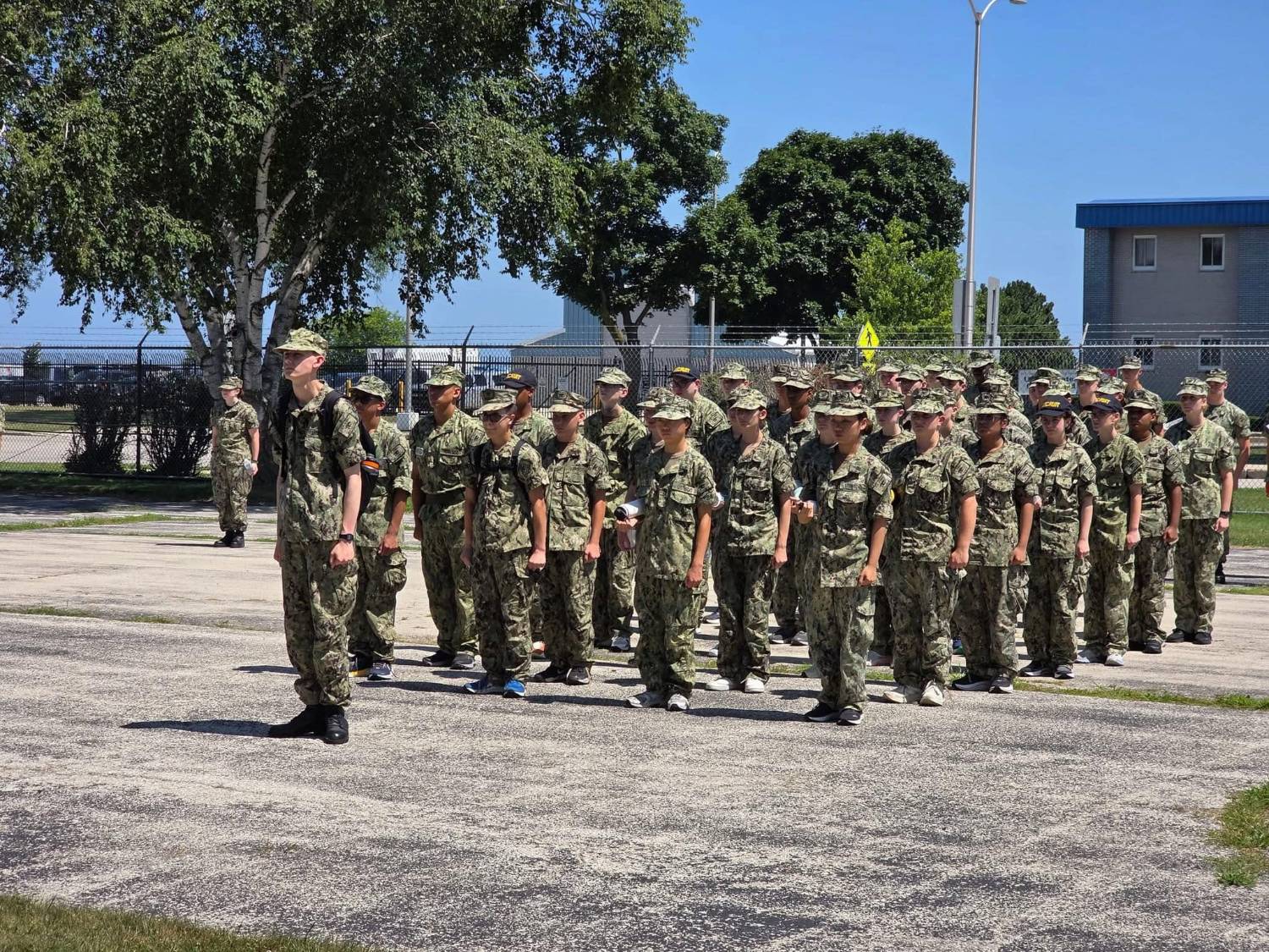 Jameson Lee standing in front of a formation of Sea Cadets in Navy Working Uniforms